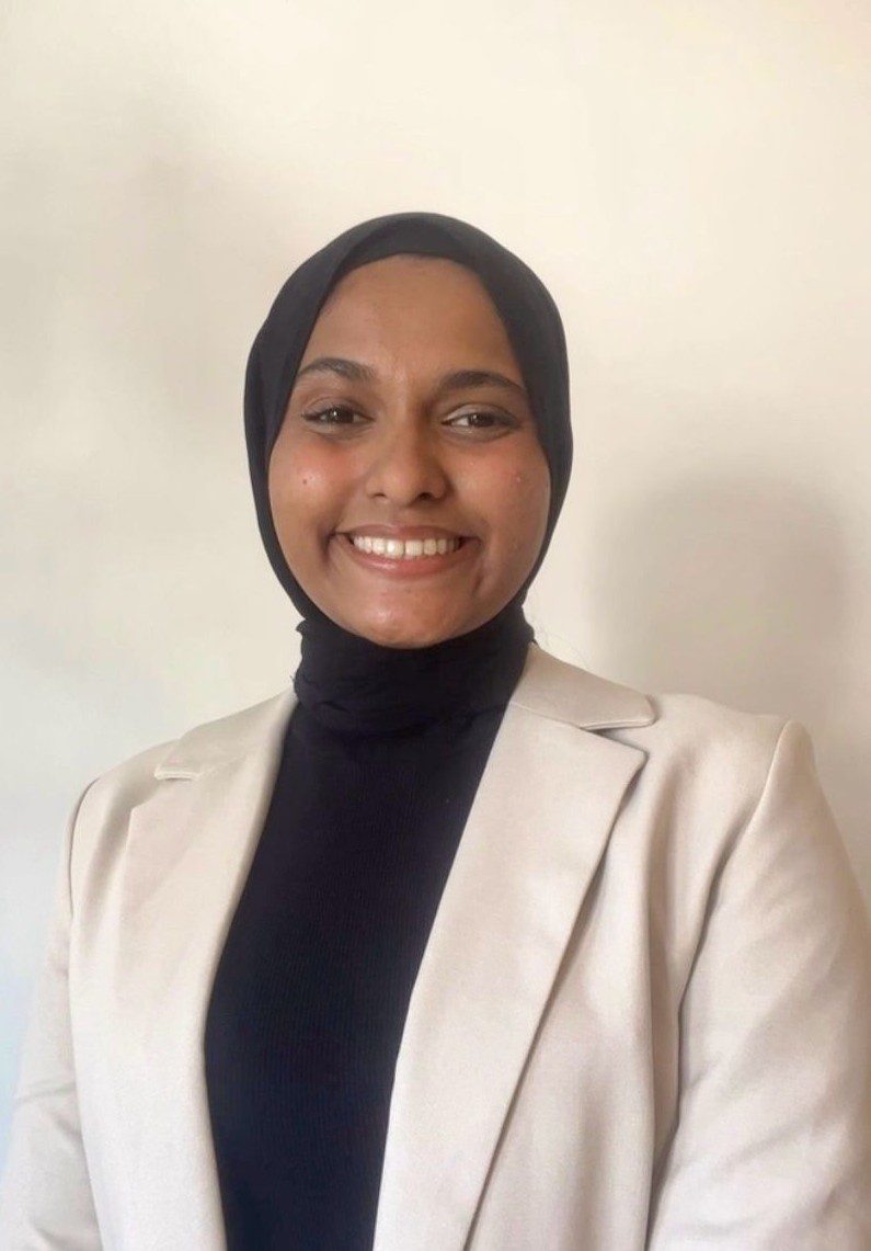 A picture of Safiya Riyaz smiling while looking straight at the camera.