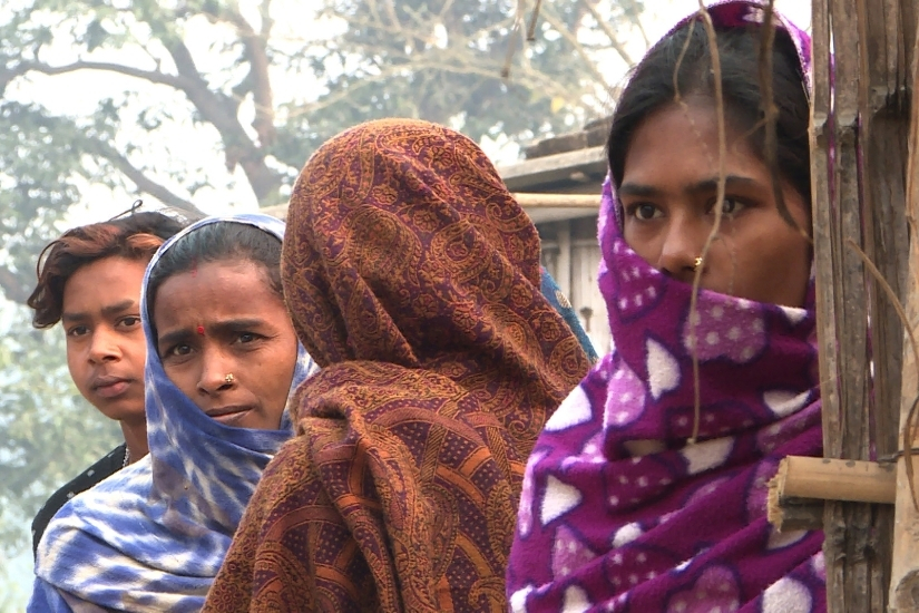 A line of Indian women and youth outdoors, standing together.